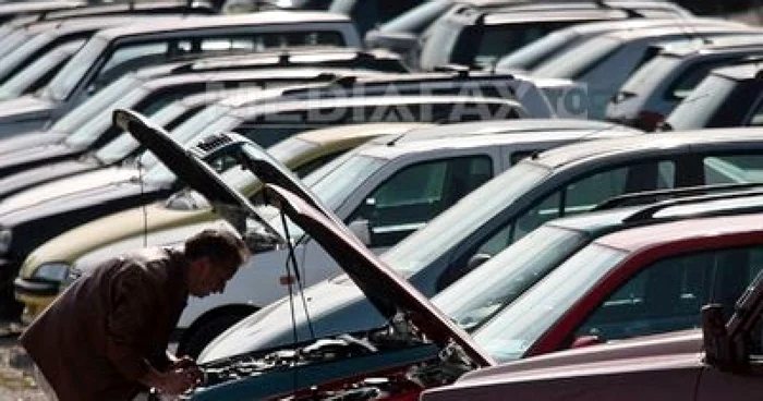 Un bărbat se uită sub capota unei mașini second hand
