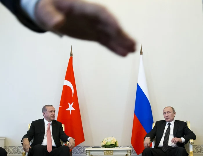 Preşedintele rus Vladimir Putin şi preşedintele turc Recep Tayyip Erdogan discută în timpul întâlnirii iar un membru al securităţii incearca sa opreasca fotografii la palatul Constantin din afara St.Petersburgului Rusia FOTO AP / Alexander Zemlianich