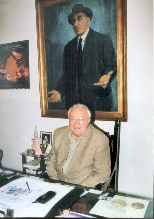 Alexandru Arşinel, într-un tablou de epocă, având celular mare pe masă. Dintre rame, Constantin Tănase priveşte îngăduitor