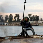 Un tânăr stă pe barca pe care o foloseşte pentru a transporta maşini şi persoane de pe cele două maluri ale râului Eufrat în centrul oraşului Raqqa în nord-estul Siriei FOTO EPA-EFE / Ahmed Mardnali