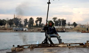 Un tânăr stă pe barca pe care o foloseşte pentru a transporta maşini şi persoane de pe cele două maluri ale râului Eufrat în centrul oraşului Raqqa în nord-estul Siriei FOTO EPA-EFE / Ahmed Mardnali