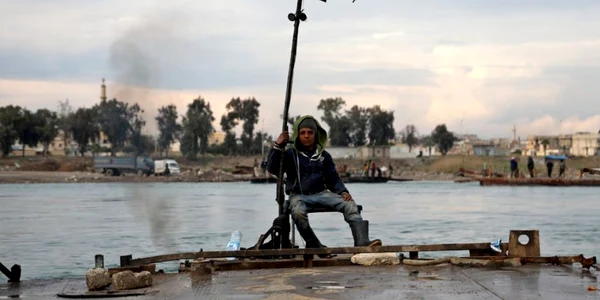 Un tânăr stă pe barca pe care o foloseşte pentru a transporta maşini şi persoane de pe cele două maluri ale râului Eufrat în centrul oraşului Raqqa în nord-estul Siriei FOTO EPA-EFE / Ahmed Mardnali