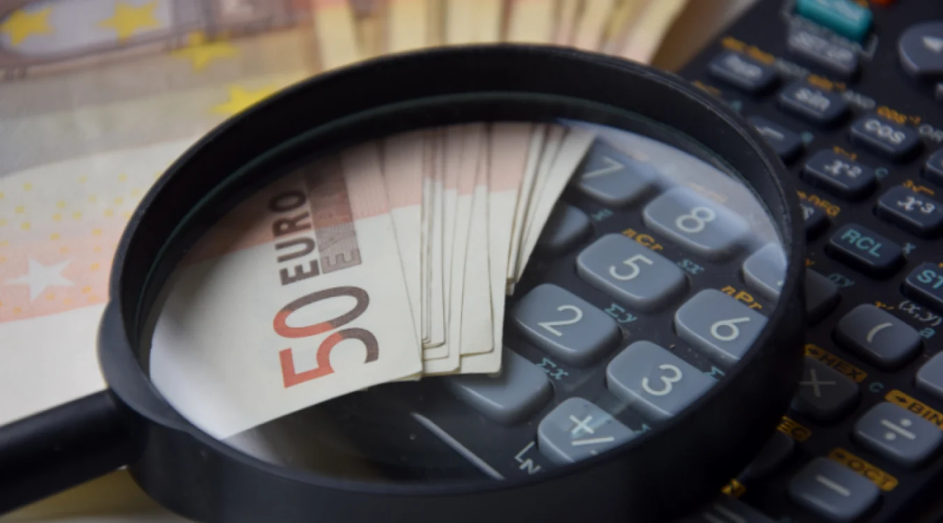 Lupa pusă pe bancnote și un calculator
