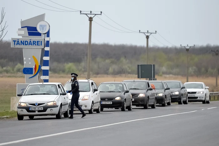 O politista efectueaza controlul documentelor soferilor, la intrarea in orasul Tandarei