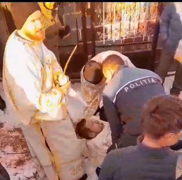 Un preot din Suceava s-a întins în faţa porţii cimitirului pentru a bloca o înmormântare VIDEO