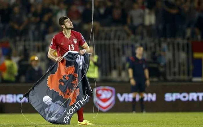 Sârbul Stefan Mitrovic luând un steag al Albaniei incluzând Kosovo, trimis pe teren cu o dronă de fanii oaspeţi într-o partidă Serbia-Albania contând pentru preliminariile Euro 2016 FOTO Reuters