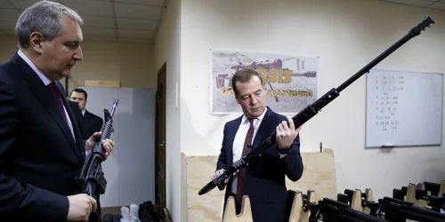 Primul ministru rus Dmitry Medvedev (D) tine o arma in timp ce asculta explicatiile adjunctului sau Dmitry Rogozinin timpul unei vizite la uzina de arme Promtechnologiya  in Moscova foto reuters