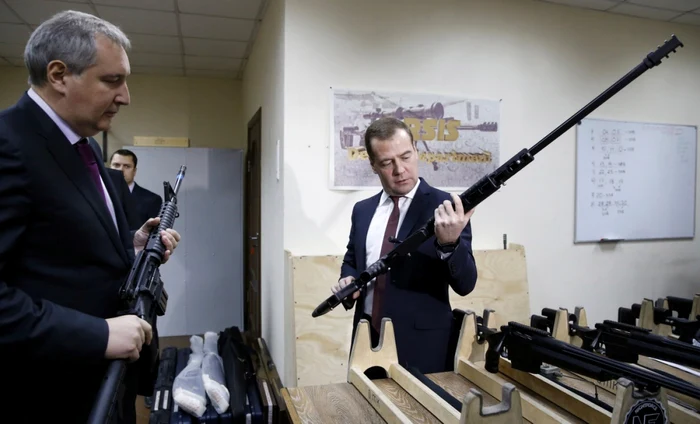 Prim-ministrul rus Dmitri Medvedev ţine o armă în timp ce
ascultă explicaţiile adjunctului sau Dmitri Rogozin. FOTO: Reuters