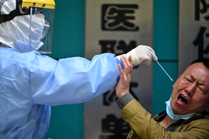 Un pacient chinez reacţionează când medicul încearcă să-l testeze pentru COVID-19. Wuhan, China, aprilie 2020. Foto AFP