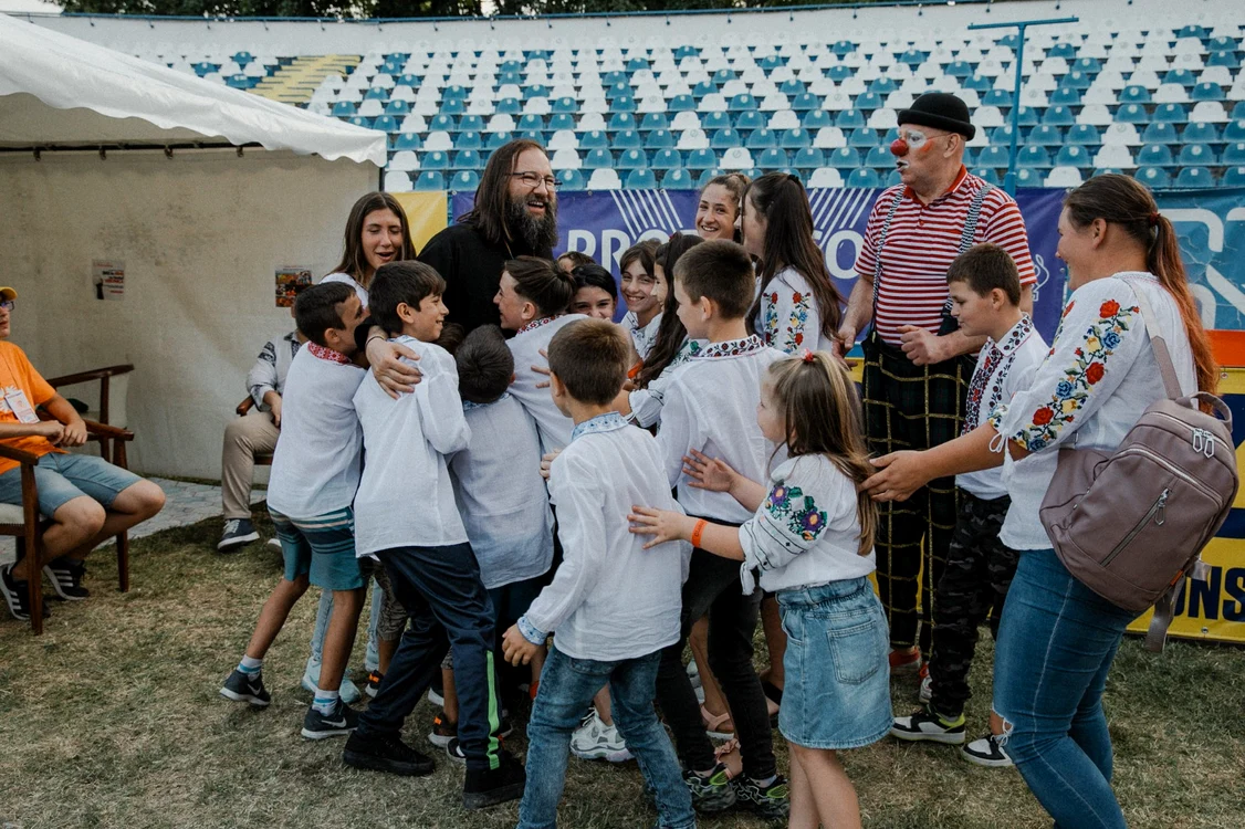 Părintele Dan Damaschin, înconjurat de copii Sursa foto: Arhiva Festivalului „Inimo”