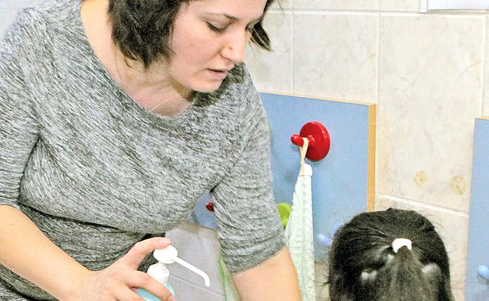 
    Educatoarele îi ajută  pe micuți să se  dezinfecteze  