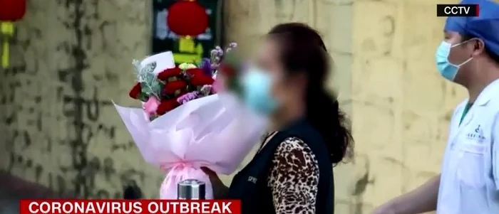 O femeie primește flori la externare după ce a fost vindecată de coronavirus