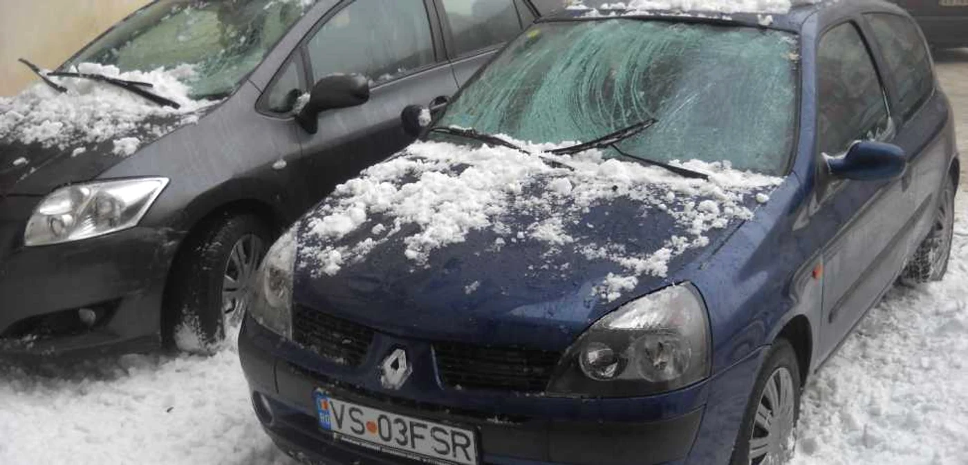 Cele două mașini au fost avariate de zăpada căzută de pe bloc
