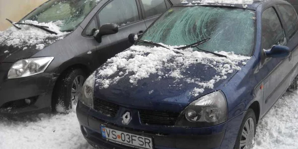 Cele două mașini au fost avariate de zăpada căzută de pe bloc
