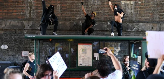 Manifestanţi protestează pe acoperişul unei staţii de autobuz în apropierea Ambasadei SUA de la Londra Foto AFP