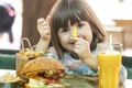 little cute girl eating fast food sandwich with fries orange juice cafe fast food concept jpg