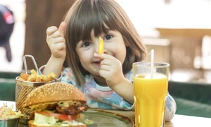 little cute girl eating fast food sandwich with fries orange juice cafe fast food concept jpg