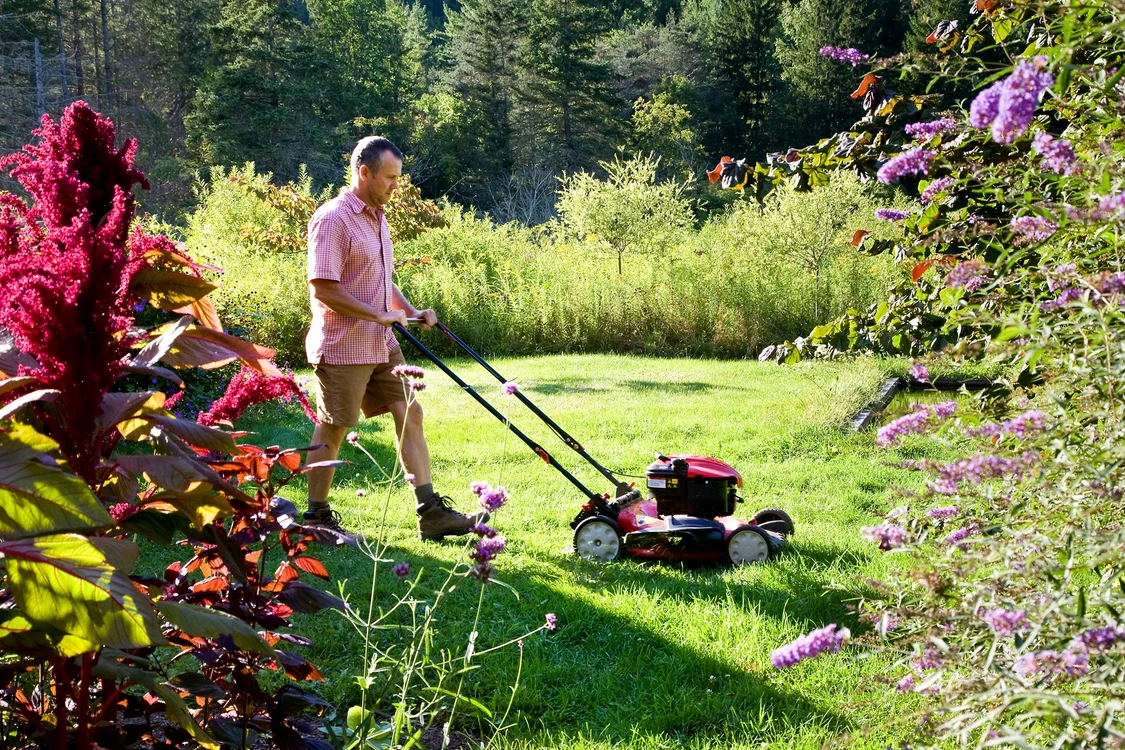 O mașină de tuns iarba în acțiune în grădină Foto Better Homes & Gardens