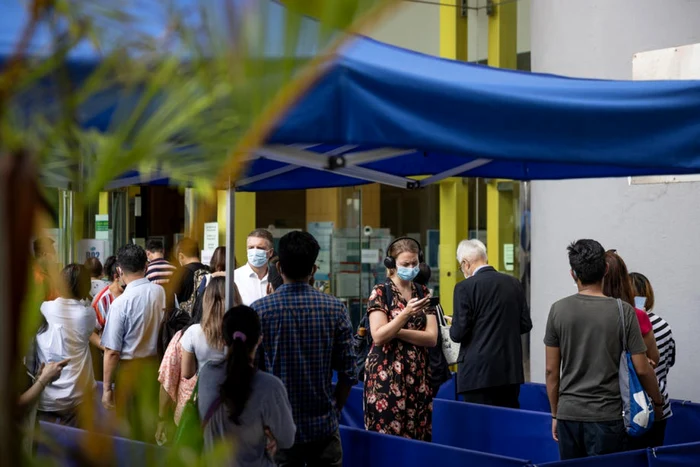 Locuitori din Hong Kong in fata unui centru de vaccinare care administrează serul anti-COVD-19 produs de Sinovac FOTO EPA-EFE