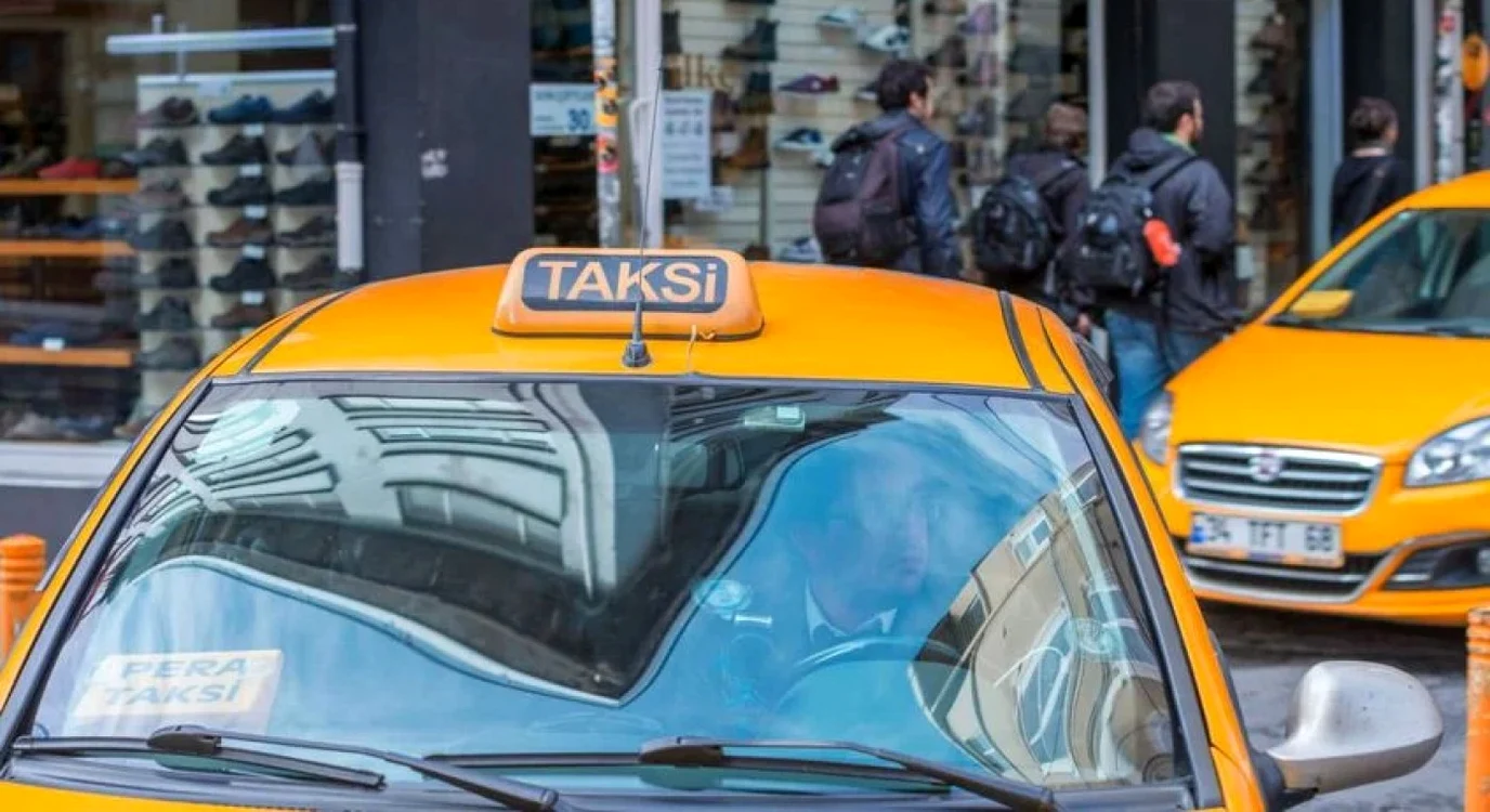 Mașină de culoare galbenă deasupra căreia este scris Taksi