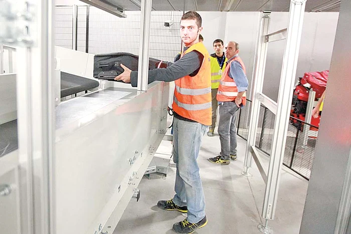 Valizele sunt aşezate de salariaţii aeroportului pe banda care le duce spre aparatele cu raze x