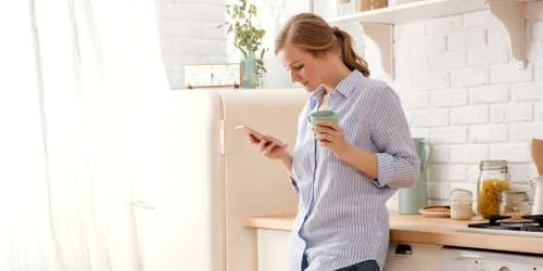 Femeie in bucatarie cauta pe telefon FOTO Shutterstock 