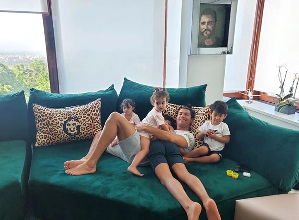 
    Cristiano Ronaldo se joacă pe canapea cu copiii. În fundal are un portret al tatălui săuFOTO: Instagram  