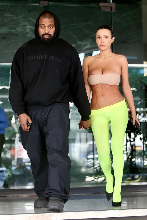 Bianca Censori ținându-se de mână cu Kanye West. Ea este îmbrăcată în colanți verzi și bustieră bej