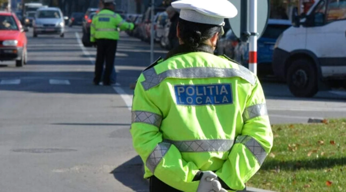 O polițistă de la locală îmbrăcată în uniformă cu părul prins și mâinile la spate
