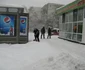 O vânzătoare curăţă de zor zăpada în faţa unui chioşc de ziare din Iaşi