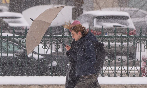 O tânără se adapostește sub o umbrela în timpul unei ninsori, in Bucuresti FOTO Mediafax - meteo - vremea- ninsoare - frig