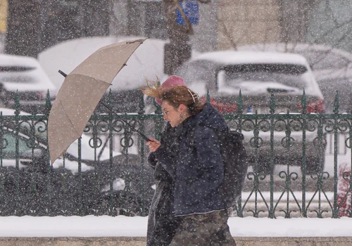  O tânără se adapostește sub o umbrela în timpul unei ninsori, in Bucuresti FOTO Mediafax - meteo - vremea- ninsoare  - frig