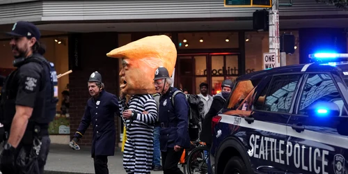 Protestatari îmbrăcați în uniforme de poliție plimbă o persoană costumată în președintele Donald Trump FOTO Profimedia