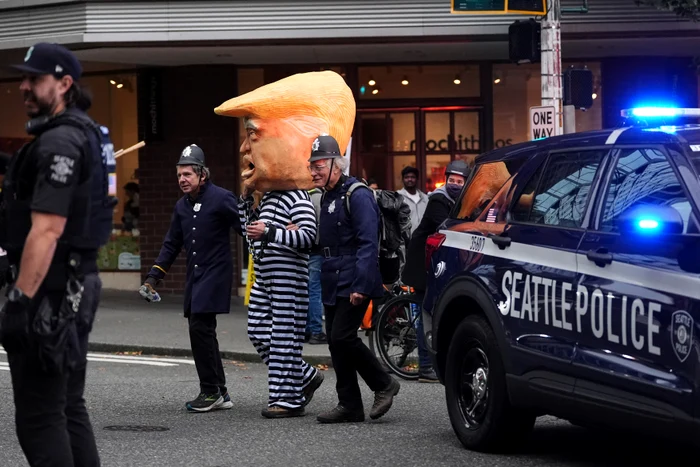Protestatari îmbrăcați în uniforme de poliție plimbă o persoană costumată în președintele Donald Trump FOTO Profimedia