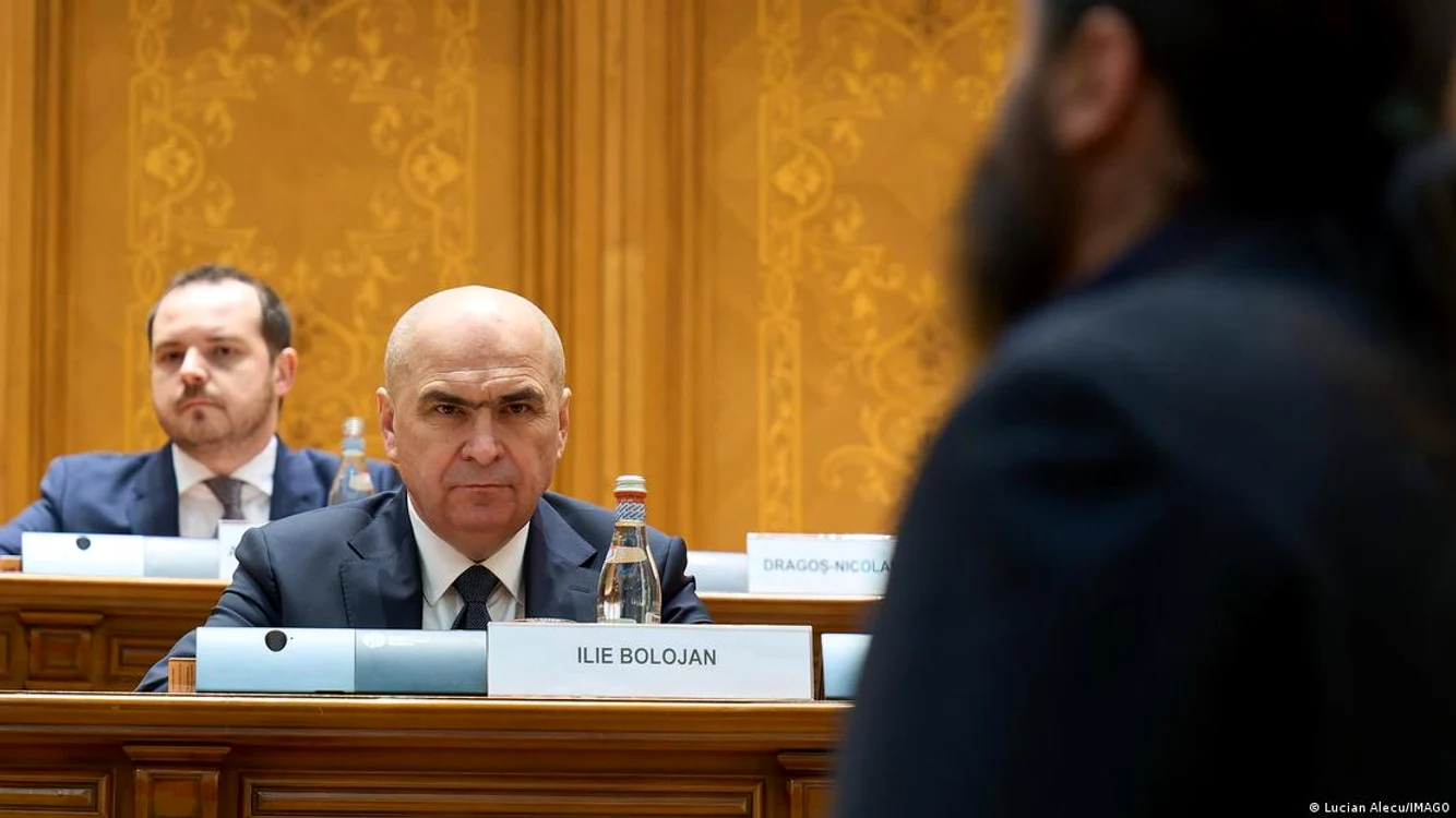 Ilie Bolojan ascultând discursurile îndreptate împotriva activităţii sale în funcţia de premier