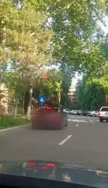 Bărbați surprinși pe capota unei mașini, în timp ce îndreptau o armă către trecători VIDEO