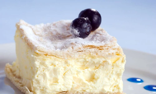 custard cake square on a plate with blueberries on blue jpeg