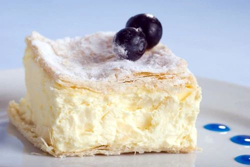 custard cake square on a plate with blueberries on blue jpeg