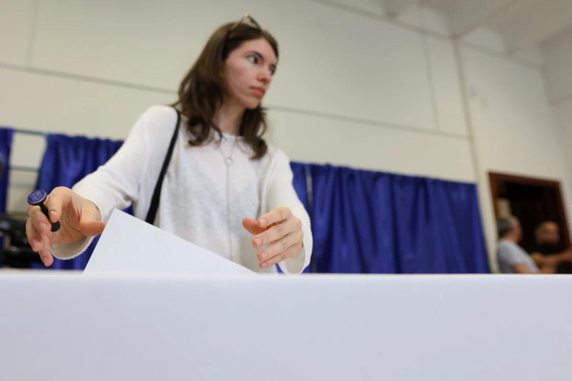 Tânără punând buletinul de vot în urnă