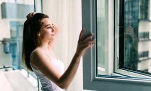 young woman opens plastic window fresh air smiling home jpg