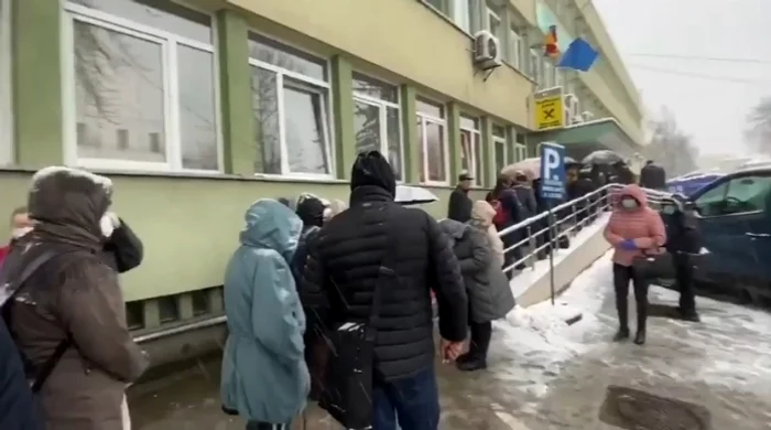 
    Bolnavii de cancer stau la coadă, în ninsoare, cu măști pe față  
