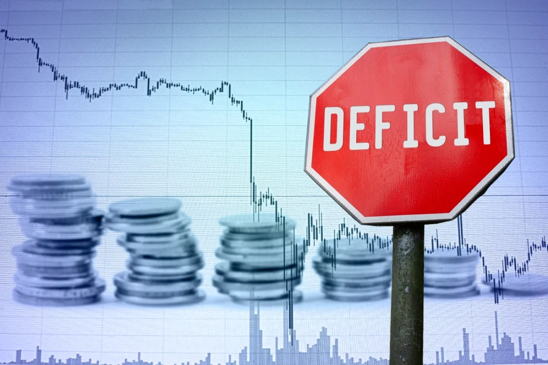 Foto cotații bursiere negative și semn de stop cu textul deficit