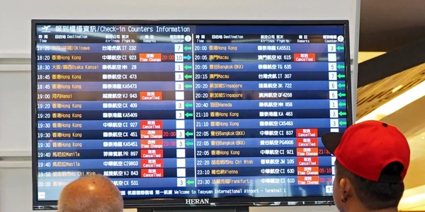 Pasagerii afla'i pe aeroportul internaţional Taoyuan privesc panourile unde sunt afişate zborurile anulate din cauza taifunului Nesat. FOTO EPA