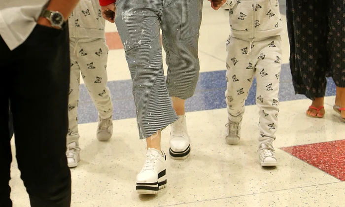 Madonna rocks a red supreme louis vuitton hoodie while touching down at JFK airport in New York holding her twins hands Estere and Stelle while Lourdes, David, and Mercy in tow after celebrating her 59th birthday in Italy jpeg