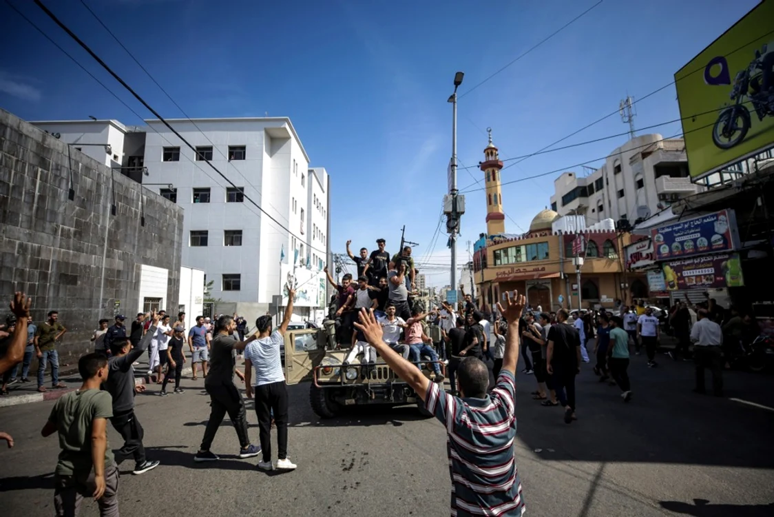 Palestinieni din Gaza salutând operațiunea de la bordul unui vehicul militar israelian FOTO EPA-EFE