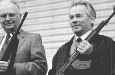 Americanul Eugene Stoner (stânga) și Mihail Kalașnikov țin în mâini puștile de asalt pe care le-au proiectat, AR-15 și AK-47, la 22 mai 1990