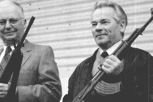 Americanul Eugene Stoner (stânga) și Mihail Kalașnikov țin în mâini puștile de asalt pe care le-au proiectat, AR-15 și AK-47, la 22 mai 1990