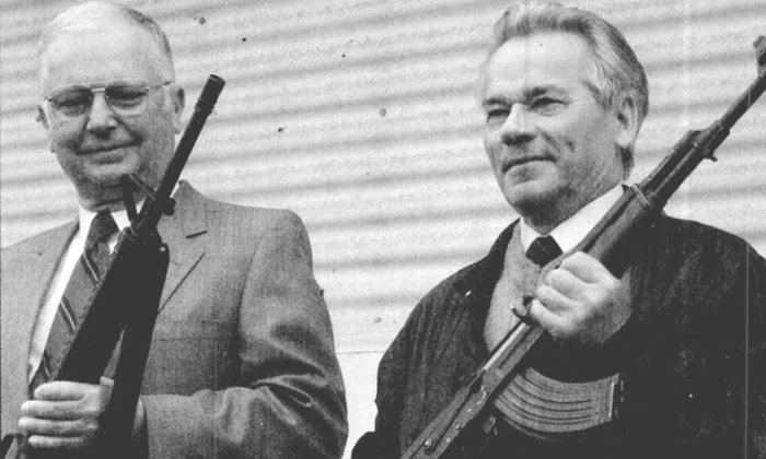 Americanul Eugene Stoner (stânga) și Mihail Kalașnikov țin în mâini puștile de asalt pe care le-au proiectat, AR-15 și AK-47, la 22 mai 1990