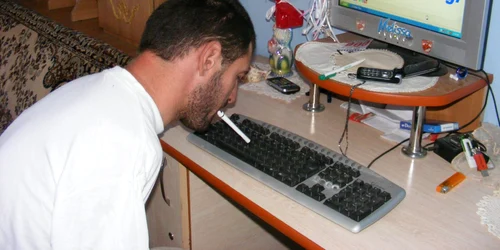 Paul Danciu tastează la calculator cu un pix ţinut între dinţi