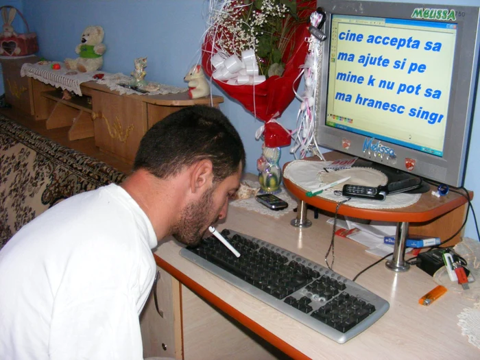 Paul Danciu tastează la calculator cu un pix ţinut între dinţi
